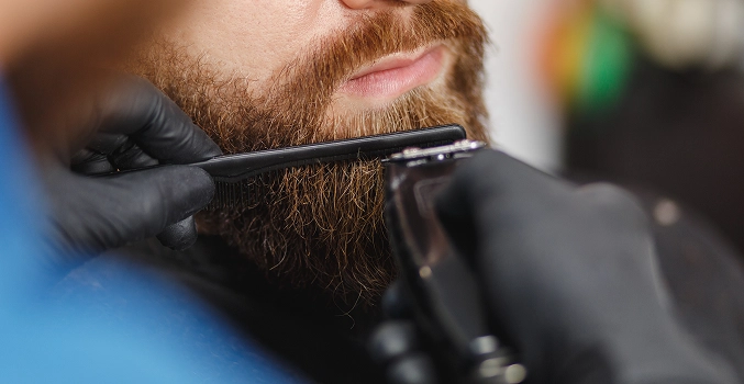 A barber trimming the beard of his client
